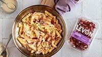 Pasta cremosa al gorgonzola con Fiammiferi di Speck Levoni servita all’interno di una padella da condividere, con crema avvolgente e bastoncini di speck in primo piano.
