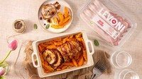 Arrosto di vitello avvolto nel Bacon italiano Levoni, dorato e appoggiato su una teglia in ceramica con fondo di cottura lucido, rametti di rosmarino fresco e carote al prezzemolo in spicchi, servito su tavola imbandita per il pranzo della domenica.
