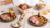 roast beef con crosta di Speck Levoni affettato al centro, con il cuore rosato ben visibile, adagiato all’interno di una pirofila con patate arrosto in spicchi e rametti di rosmarino fresco, appoggiato sopra un tagliere e su una tavola imbandita con elementi naturali. 