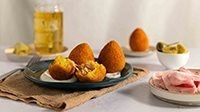 Arancini di riso con Prosciutto Cotto Alta Qualità Levoni e mozzarella filante, dorati e croccanti, serviti su piatto rustico con carta da fritto, erbe aromatiche e fili di mozzarella che si sciolgono al taglio.